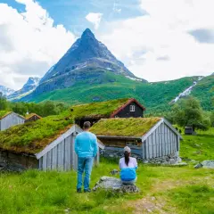 Para planujących ubezpieczenie Norwegia: para podziwia malownicze chatki z zielonymi dachami i górski krajobraz.