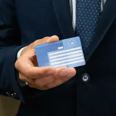 Mężczyzna trzyma Europejską Kartę Ubezpieczenia Zdrowotnego. Ważność karty EKUZ jest kluczowa dla podróżujących po Europie.