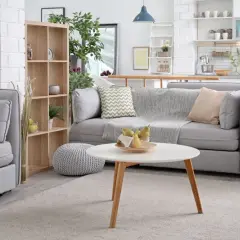 Nowoczesny salon z aneksem kuchennym. Miękka sofa, stolik kawowy z owocami i kosz na pranie. To wszystko warto objąć ubezpieczeniem mienia.