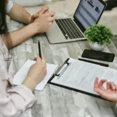 Rozmowa o tym, jak zrezygnować z OC. Na stole dokumenty, laptop i telefon.
