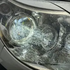 Krople deszczu na reflektorze, który świeci, sugerują jazda bez jednego światła.