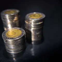 Stosy monet pięciozłotowych na ciemnym tle. Zastanawiasz się, jakie odszkodowanie za przekopanie działki?