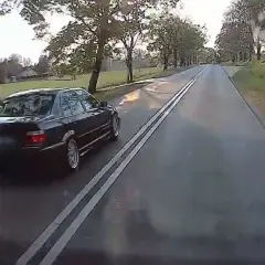 Czarny sedan jedzie po drodze z podwójną ciągłą. Czy można wyprzedzać na podwójnej ciągłej? To pytanie zadaje sobie wielu kierowców.