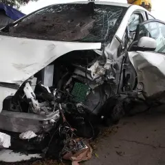 Brak przeglądu i stłuczka. Biały samochód po wypadku, zniszczony przód i drzwi, wybitą szybę.