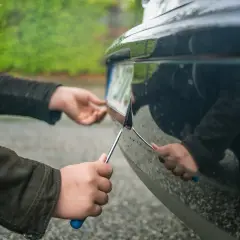 Osoba przykręca tablicę rejestracyjną do zderzaka. To ważny krok przed rejestracją auta, a ubezpieczenie OC niezarejestrowanego auta jest niemożliwe.