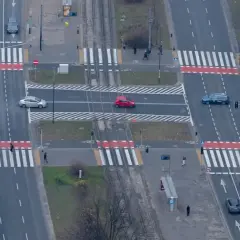 Skrzyżowanie z przejściami dla pieszych. Czerwony samochód wykonuje wyprzedzanie na pasach, ignorując pieszych.