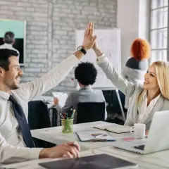 Sukcesja co to? Dwóch współpracowników świętuje sukces w biurze, podając sobie piątkę.