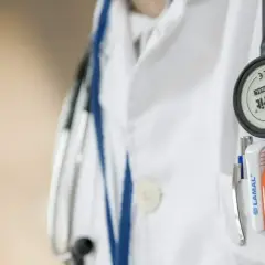Lekarz w białym kitlu, z przypiętym stetoskopem, przygotowuje się do skierowania na badania psychiatryczne przez sąd.