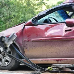 Zniszczony czerwony samochód na lawecie. Widać, ile wzrasta oc po szkodzie, gdy auto jest tak uszkodzone.