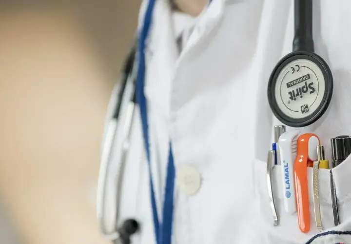 Lekarz w białym kitlu, z przypiętym stetoskopem, przygotowuje się do skierowania na badania psychiatryczne przez sąd.