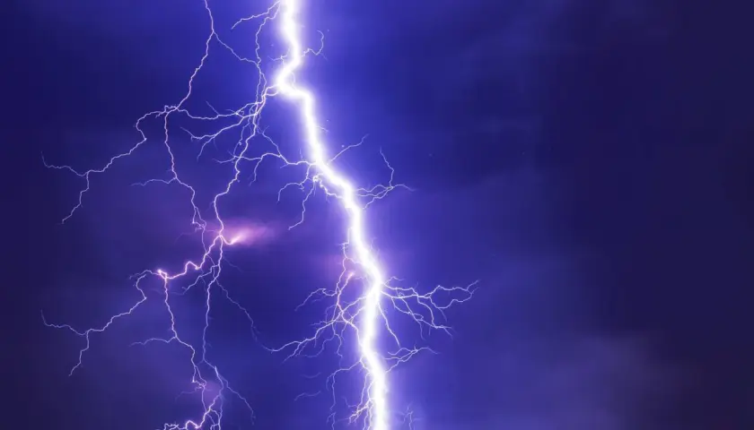 Potężne wyładowanie atmosferyczne rozświetla nocne niebo. Takie przepięcie prądu może spowodować szkody, ale warto pamiętać o możliwości uzyskania odszkodowania.