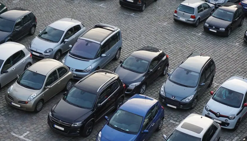 Parking tylko dla mieszkańców, mandat grozi za parkowanie. Wiele samochodów na brukowanym placu.