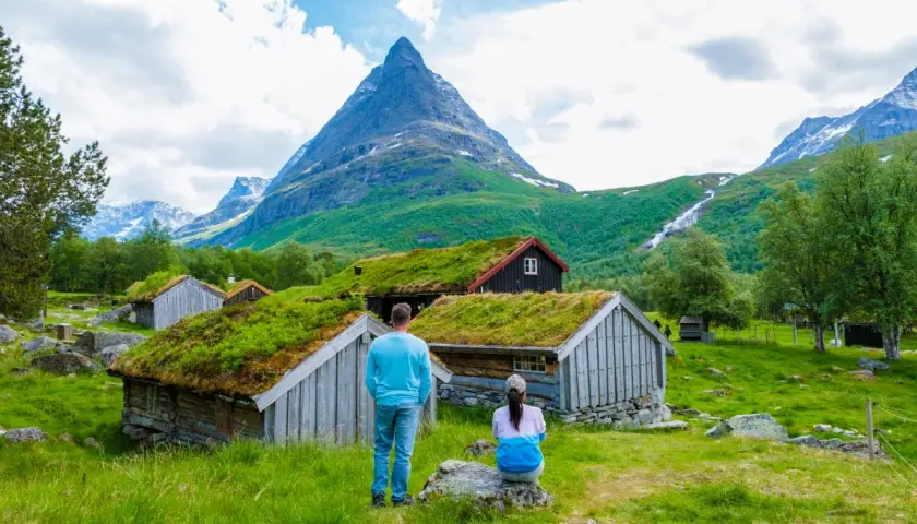 Para planujących ubezpieczenie Norwegia: para podziwia malownicze chatki z zielonymi dachami i górski krajobraz.