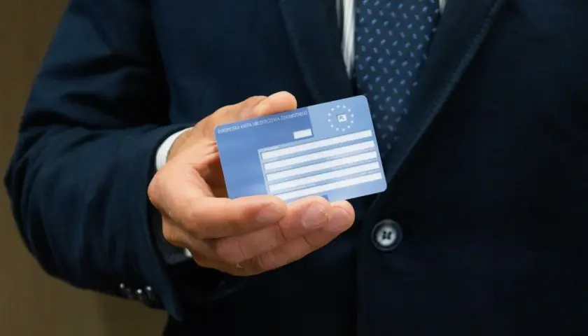 Mężczyzna trzyma Europejską Kartę Ubezpieczenia Zdrowotnego. Ważność karty EKUZ jest kluczowa dla podróżujących po Europie.