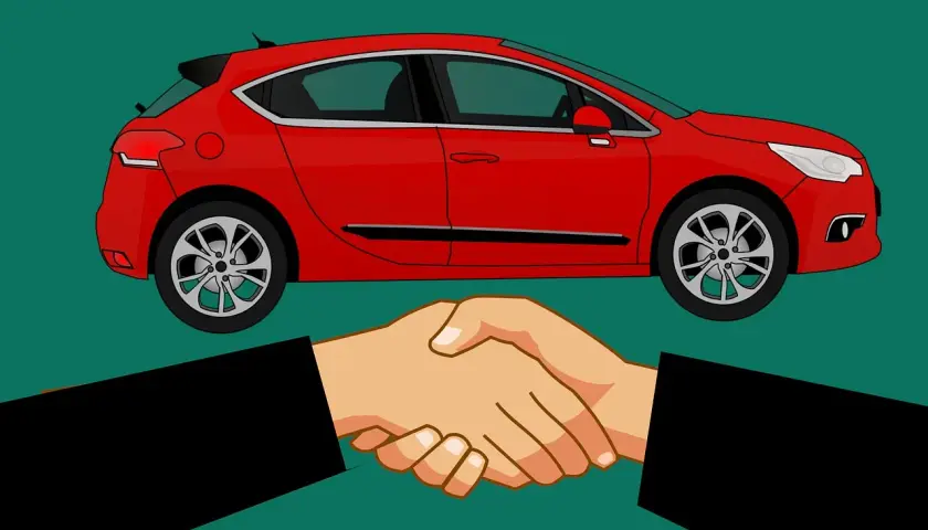 Sprzedałem auto i nie wypowiedziałem umowy OC. Dwie dłonie ściskają się na tle czerwonego samochodu.