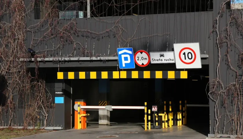 Znaki drogowe przy wjeździe na parking pod blokiem: zakaz wjazdu pojazdów o wysokości powyżej 2m, strefa ruchu, ograniczenie prędkości do 10 km/h.