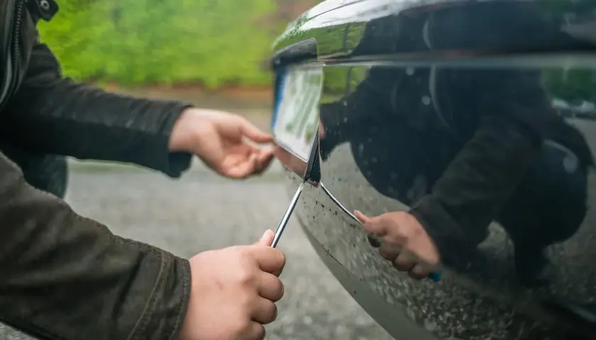 Osoba przykręca tablicę rejestracyjną do zderzaka. To ważny krok przed rejestracją auta, a ubezpieczenie OC niezarejestrowanego auta jest niemożliwe.