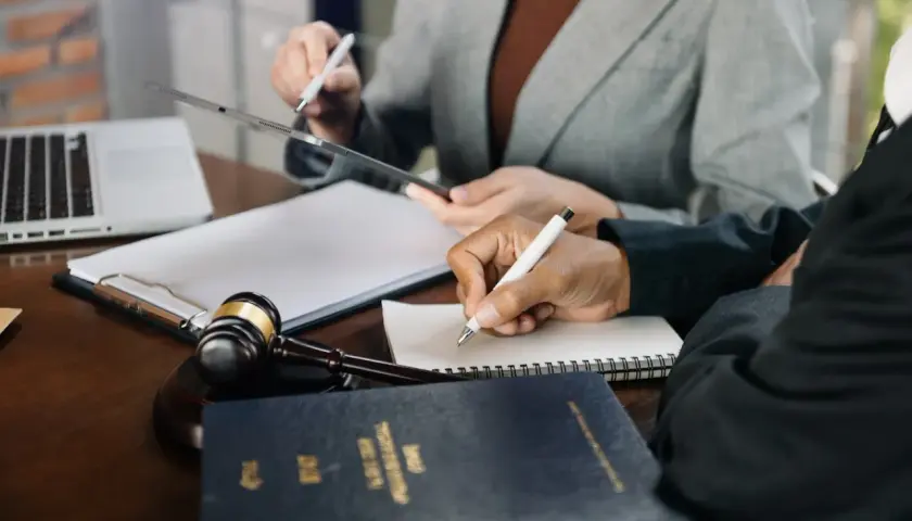 Prawnicy analizują dokumenty, dyskutując o potencjalnej dewastacji. Na stole młotek sędziowski i laptop.