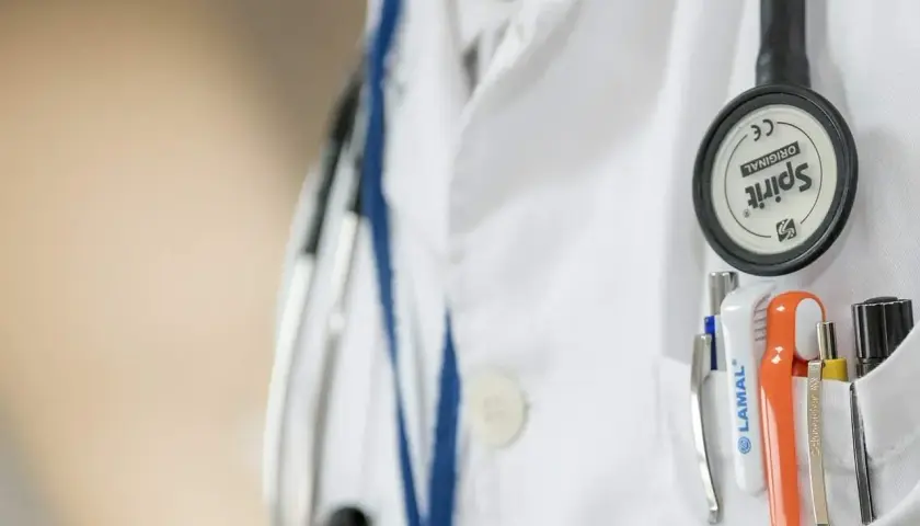 Lekarz w białym kitlu, z przypiętym stetoskopem, przygotowuje się do skierowania na badania psychiatryczne przez sąd.
