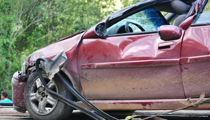 Zniszczony czerwony samochód na lawecie. Widać, ile wzrasta oc po szkodzie, gdy auto jest tak uszkodzone.