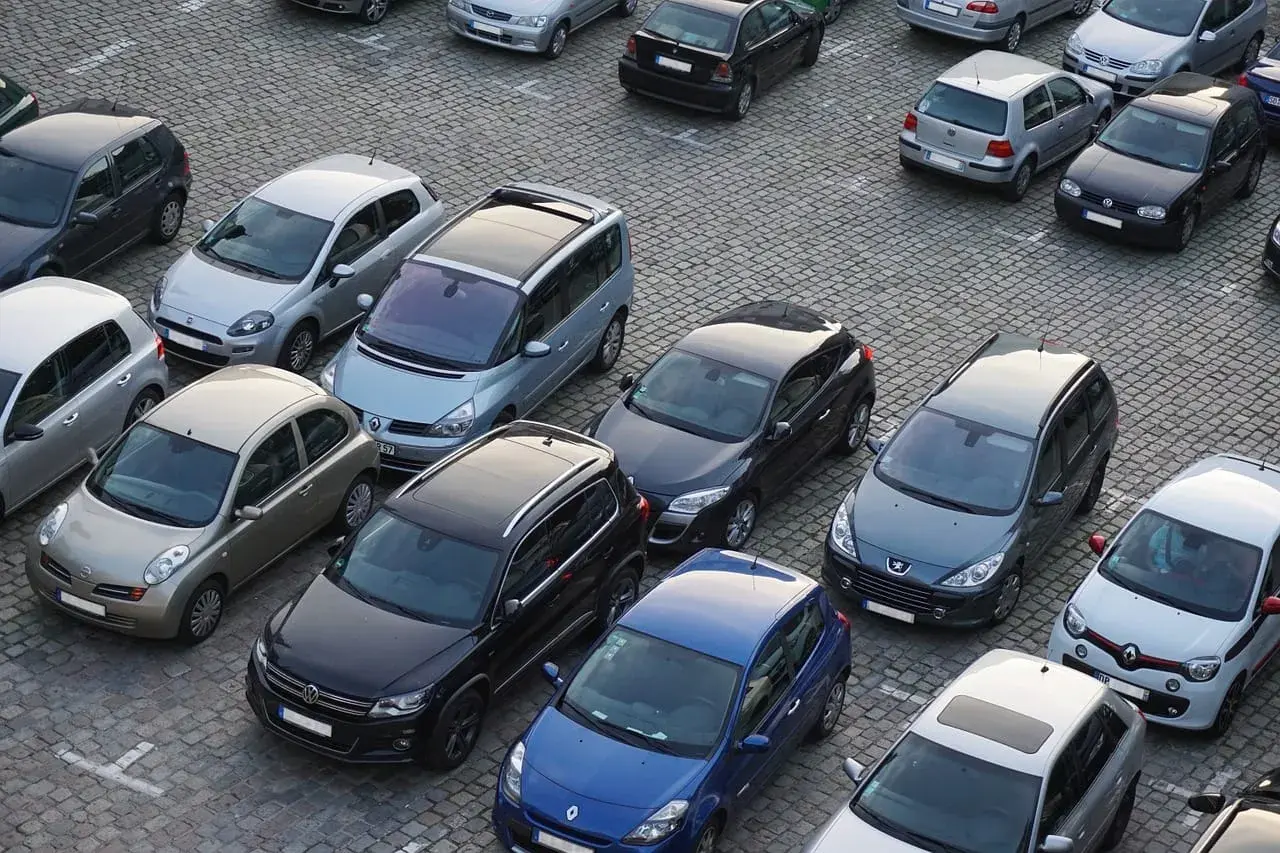 Parking tylko dla mieszkańców, mandat grozi za parkowanie. Wiele samochodów na brukowanym placu.