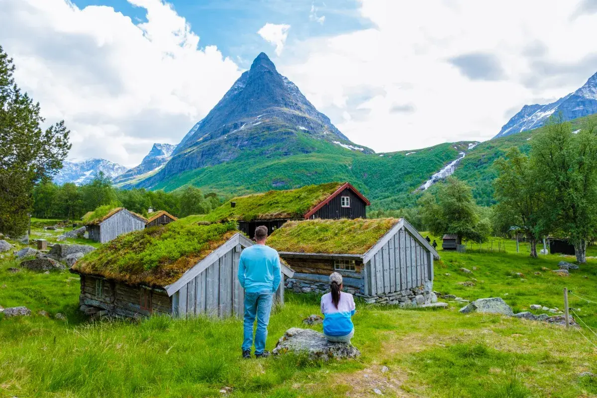 Para planujących ubezpieczenie Norwegia: para podziwia malownicze chatki z zielonymi dachami i górski krajobraz.