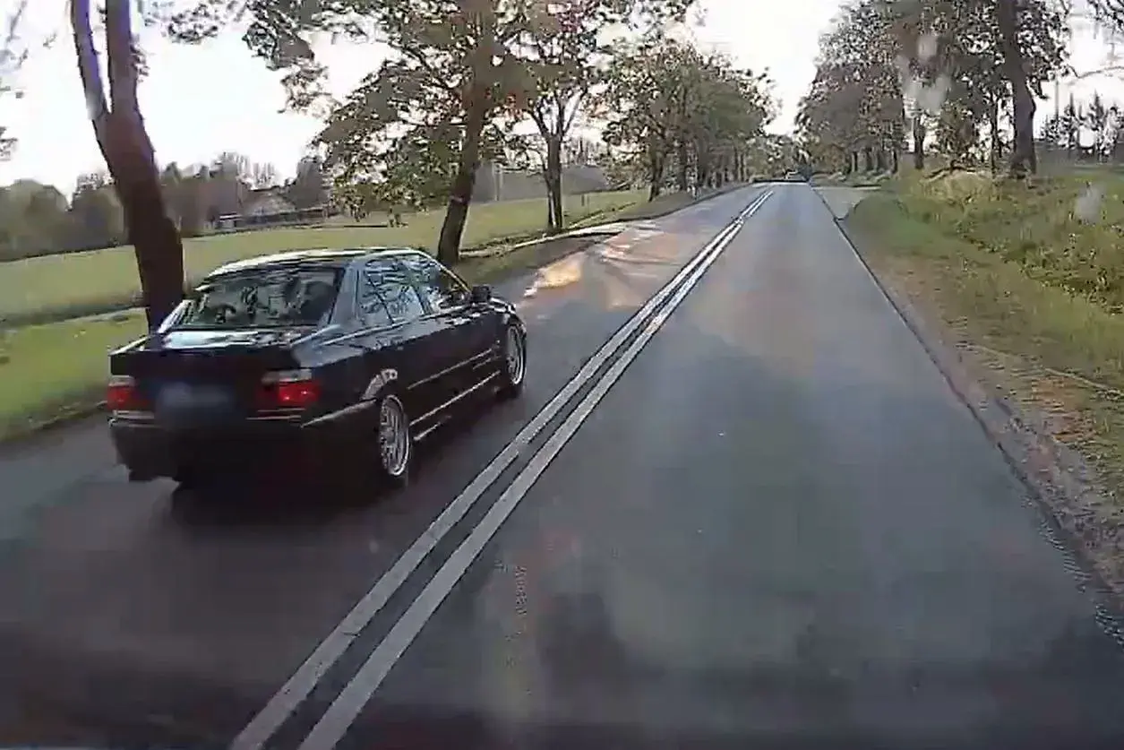 Czarny sedan jedzie po drodze z podwójną ciągłą. Czy można wyprzedzać na podwójnej ciągłej? To pytanie zadaje sobie wielu kierowców.