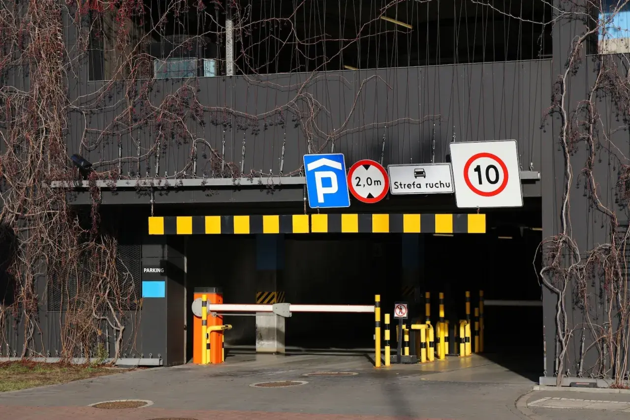 Znaki drogowe przy wjeździe na parking pod blokiem: zakaz wjazdu pojazdów o wysokości powyżej 2m, strefa ruchu, ograniczenie prędkości do 10 km/h.