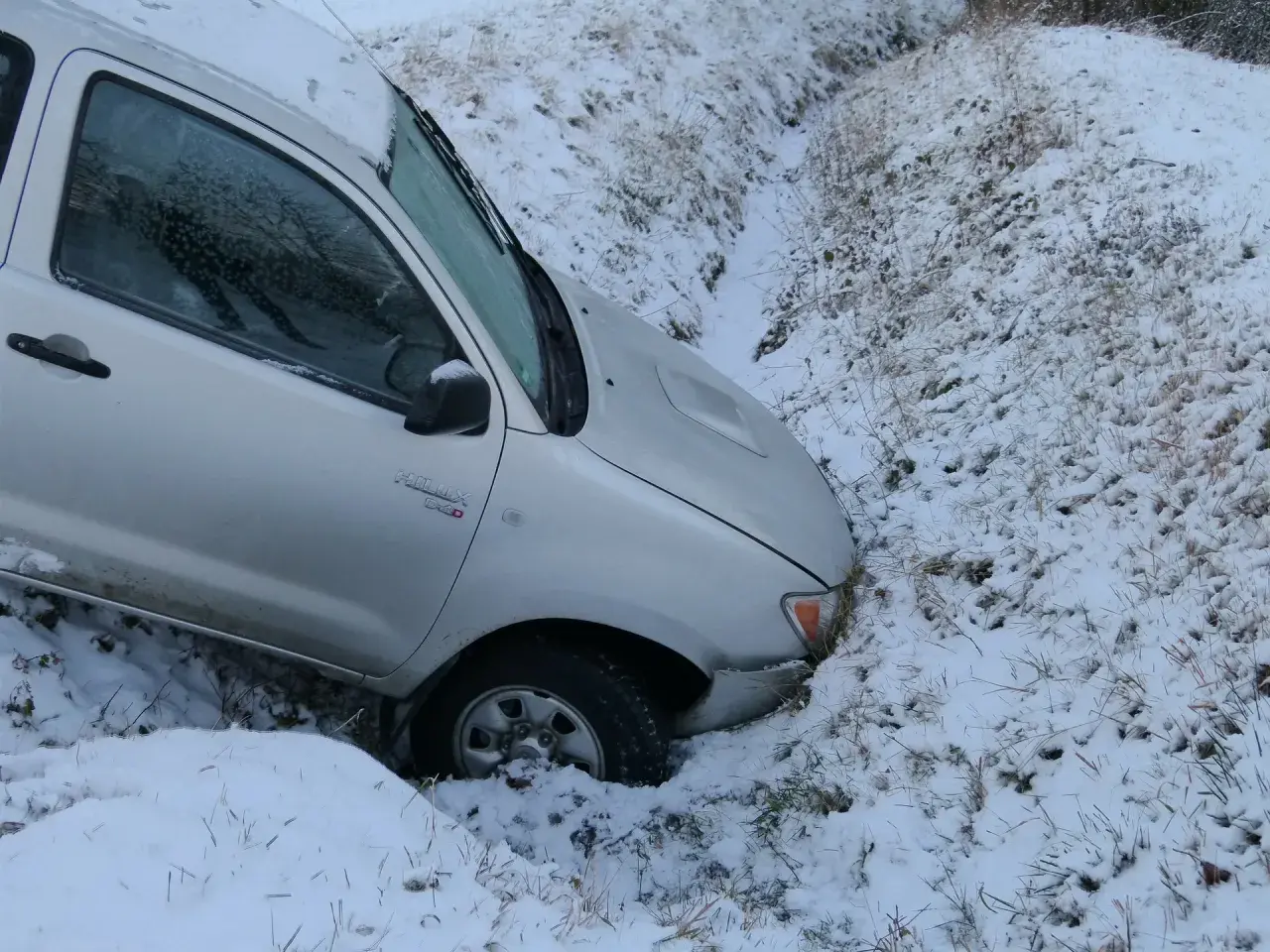 Srebrny pickup wpadł do rowu w śniegu. Kierowca pewnie żałuje, że pierwsza rata OC po terminie, bo teraz czeka go laweta.