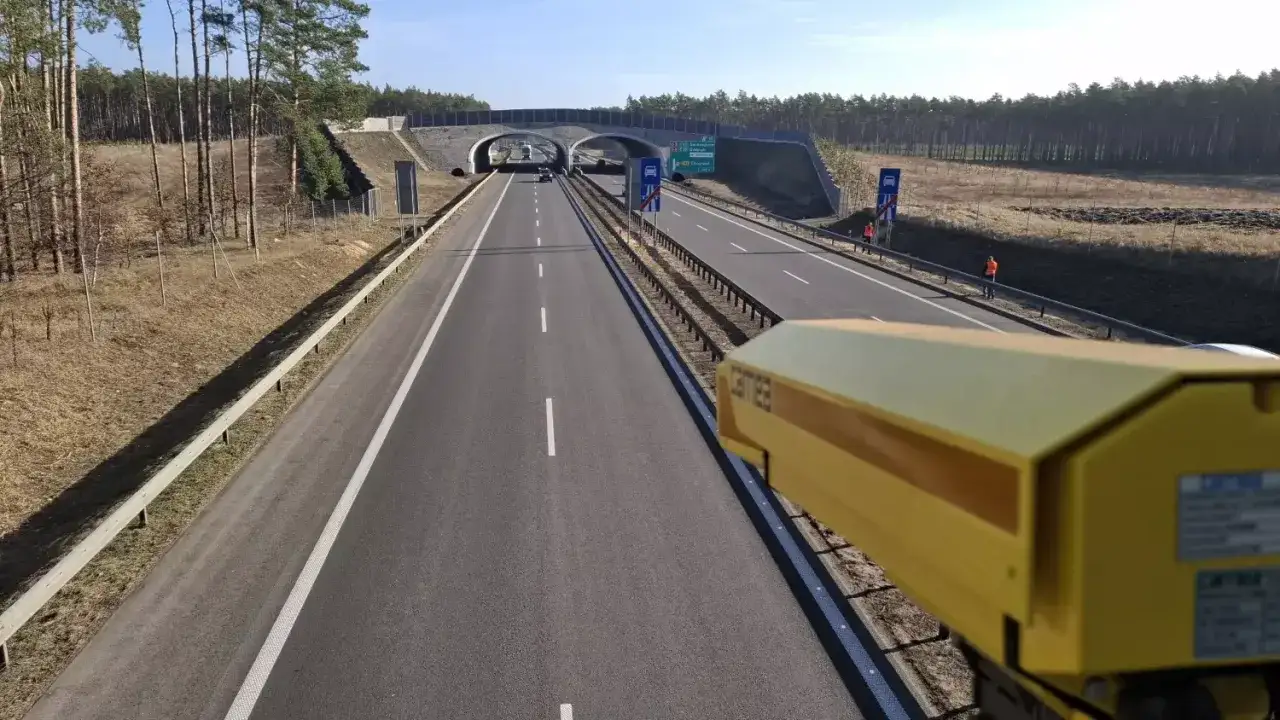 Żółta kamera odcinkowego pomiaru prędkości na pustej drodze. Zastanawiasz się, po jakim czasie przychodzi mandat z odcinkowego pomiaru prędkości?
