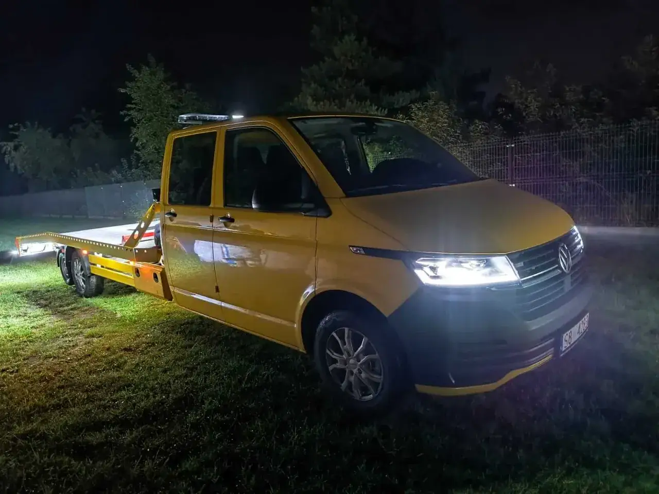Żółty laweta nocą, gotowa do pomocy. Ubezpieczenie assistance co to? To spokój na drodze, gdy potrzebujesz wsparcia.