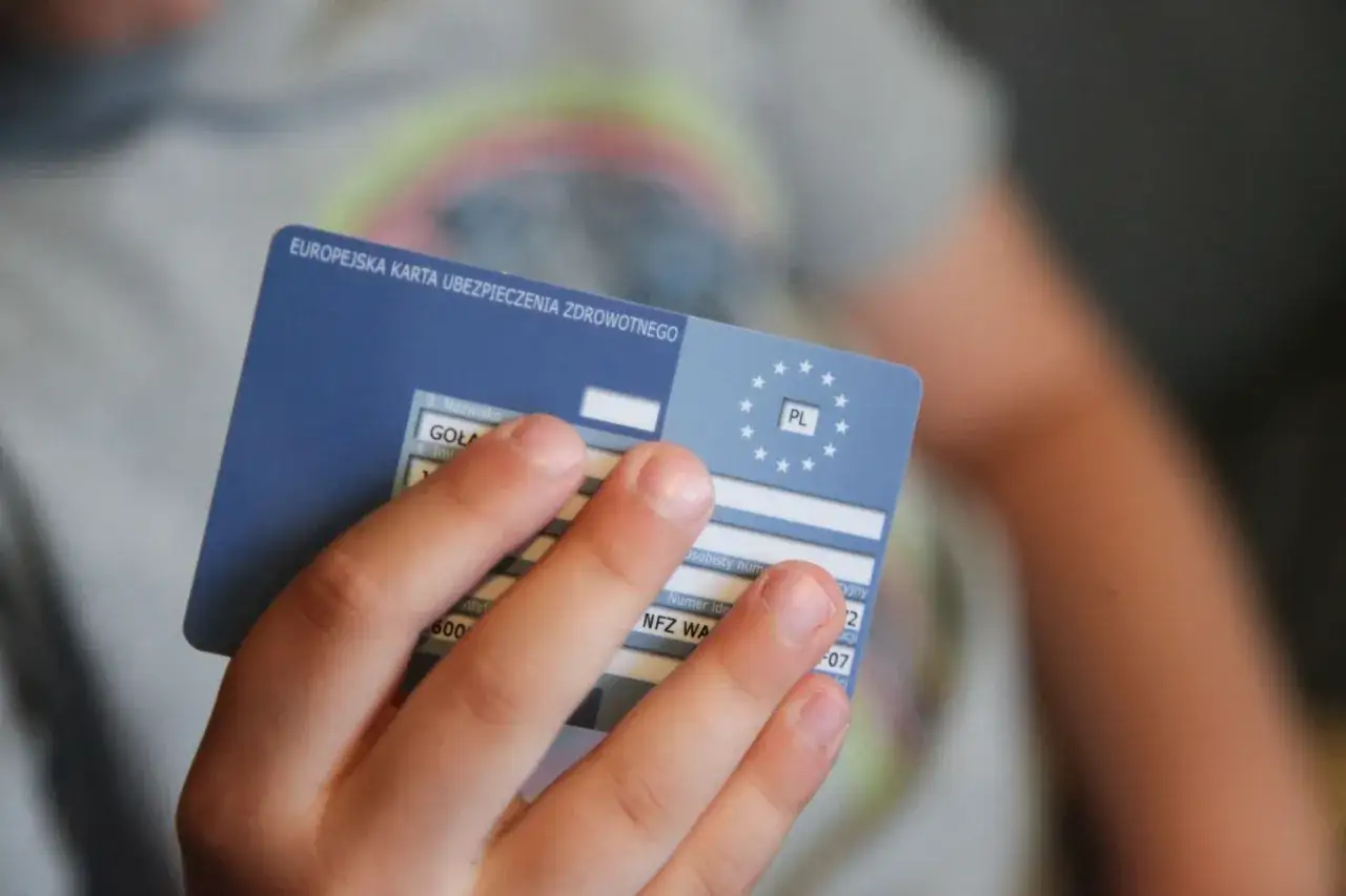 Dziecko trzyma Europejską Kartę Ubezpieczenia Zdrowotnego. Ważność karty EKUZ jest kluczowa dla podr&oacute;żujących po Europie.