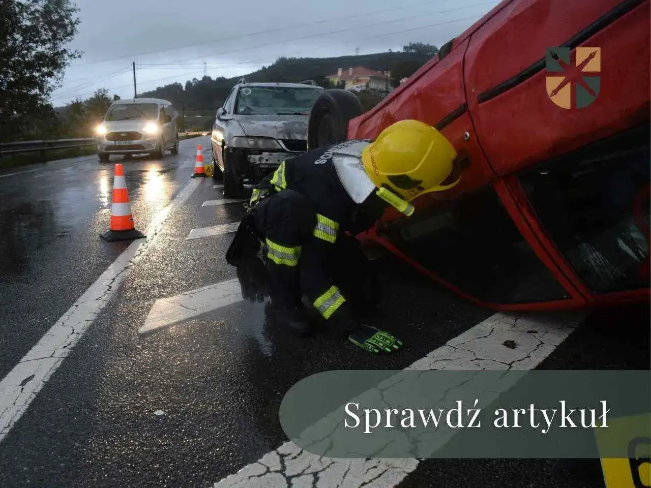 Strażak bada miejsce wypadku drogowego, gdzie przewrócony czerwony samochód leży na boku. W tle widać inne pojazdy i znaki ostrzegawcze. Artykuł dotyczy zadośćuczynienia po wypadku.