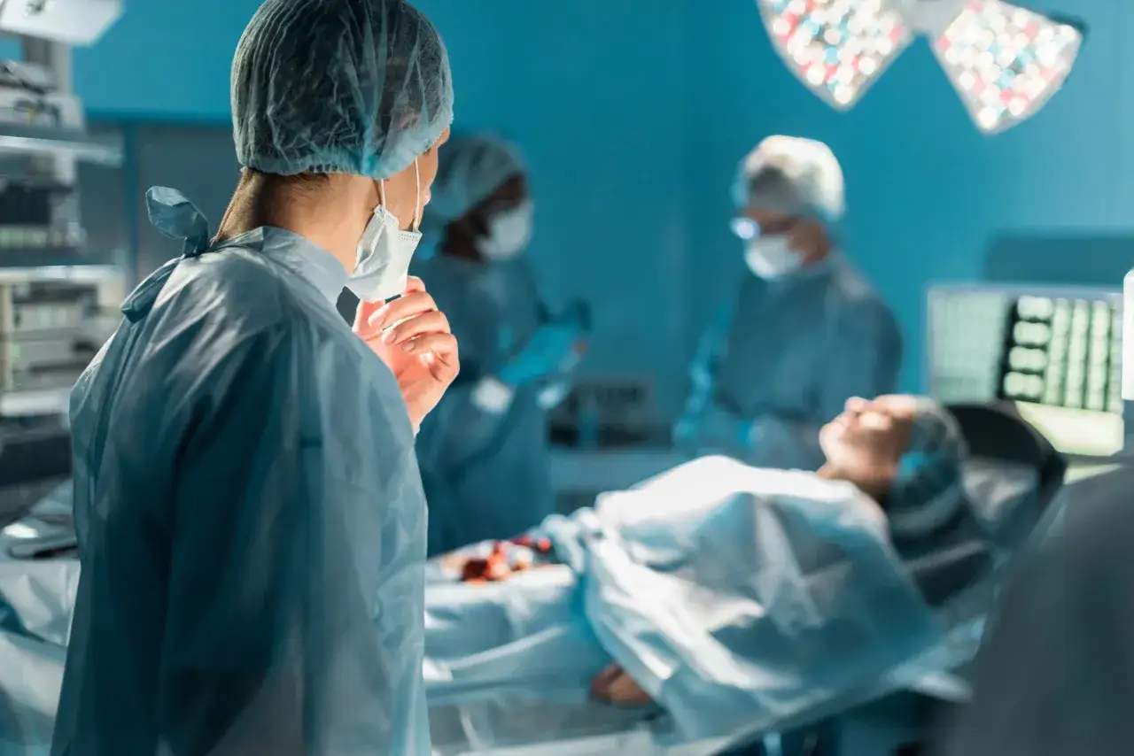 Zespół medyczny podczas zabiegu. Pacjent na stole operacyjnym, lekarze w maseczkach i czepkach. Możliwe, że to przygotowania do koronarografii, po której można ubiegać się o odszkodowanie.