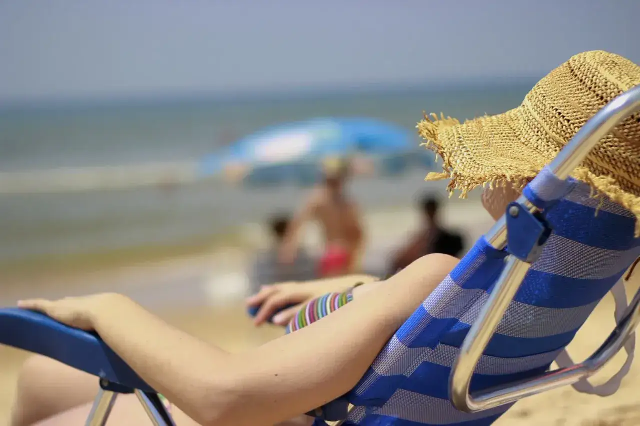 Osoba w słomkowym kapeluszu odpoczywa na plaży. Może to być moment relaksu po otrzymaniu odszkodowania od biura podr&oacute;ży.