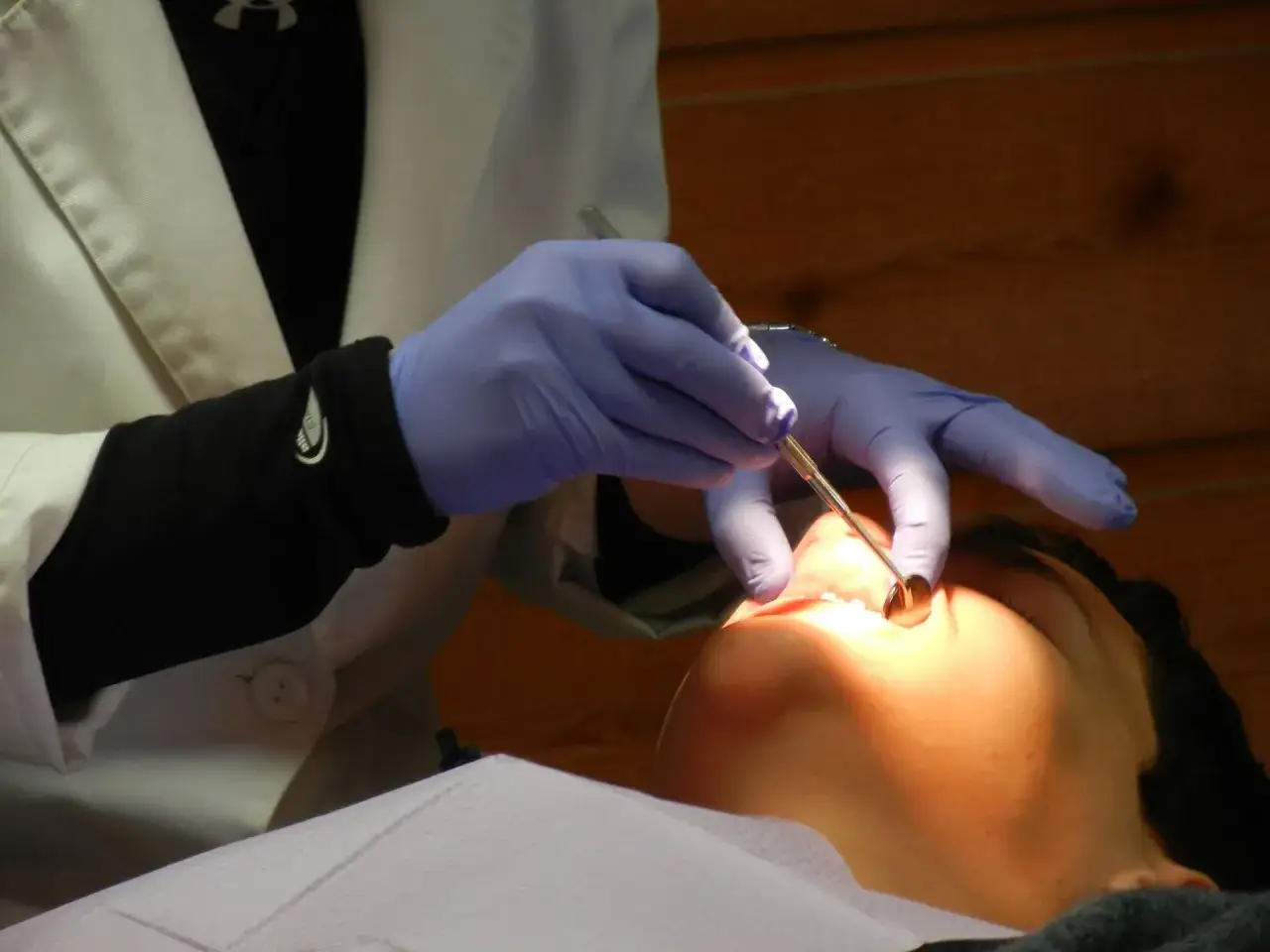Dentysta bada ząb pacjenta, być może w celu oceny reklamacji plomby.