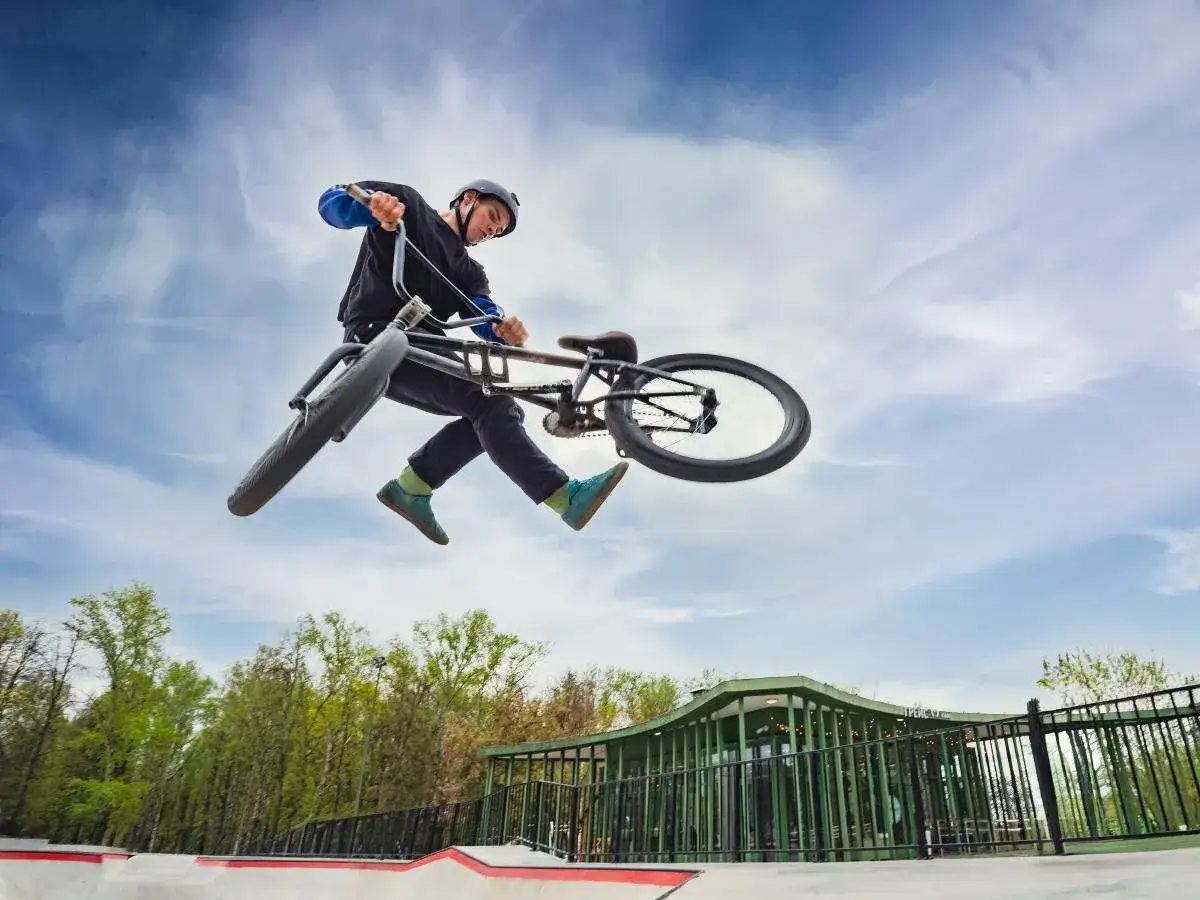 Chłopak na rowerze BMX wykonuje trik w powietrzu. Bezpieczeństwo w sportach ekstremalnych jest kluczowe, dlatego warto pomyśleć o ubezpieczeniu.